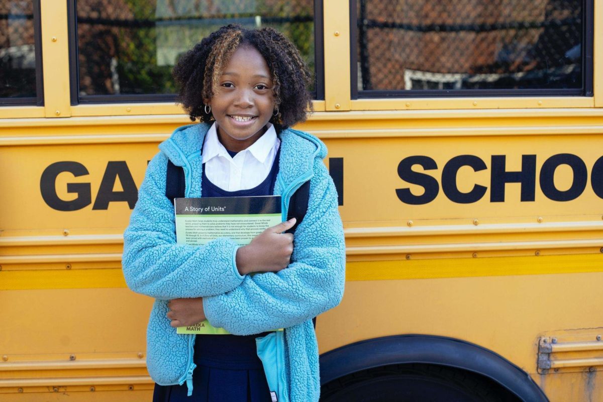 girl is standing in front of yellow school bus