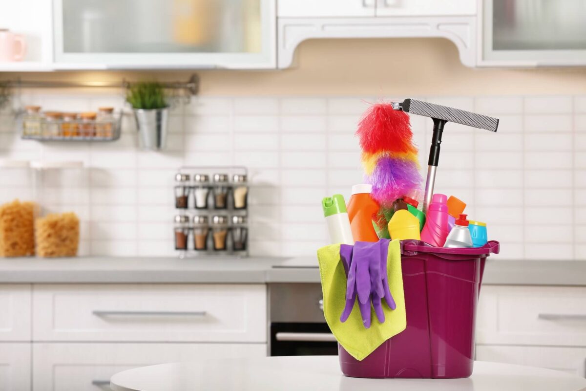 A bucket of cleaning products in front of a kitchen