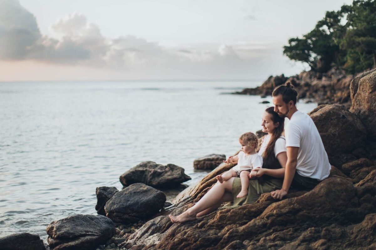 A family sitting on a rocky shore