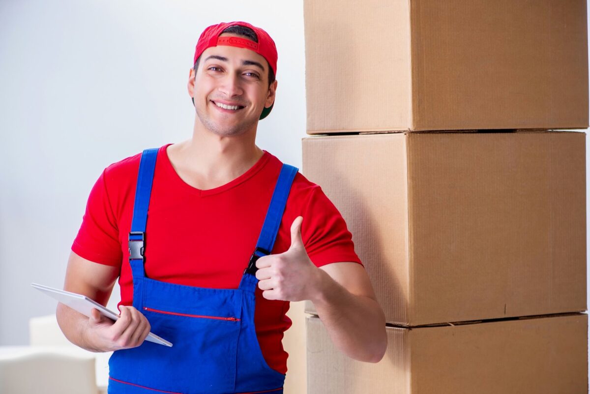 Professional mover holding a thumbs up in front of boxes