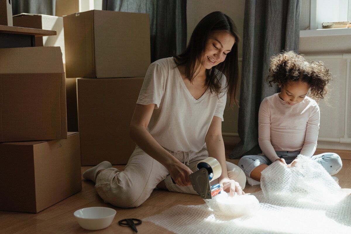 A woman and a girl packing things together and smiling