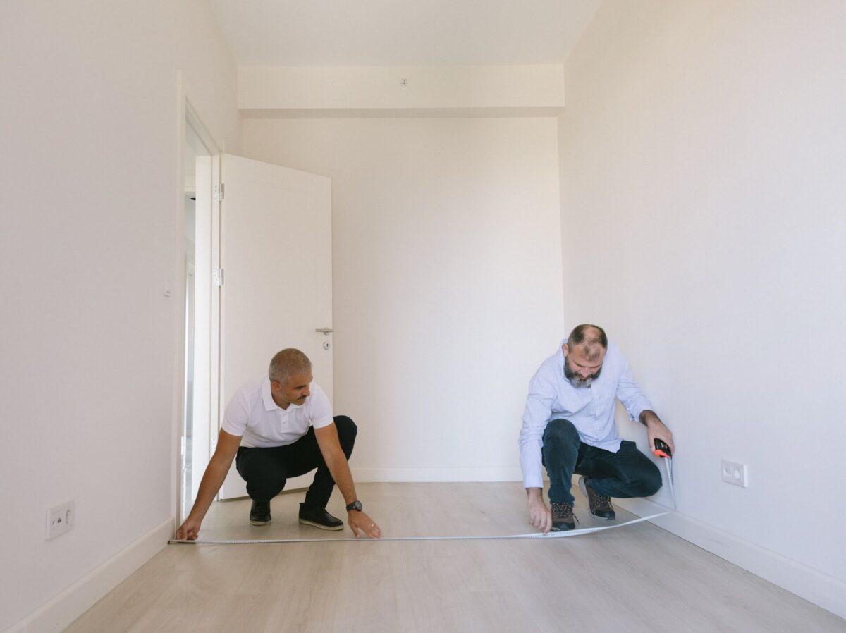 Two men measuring the length of a room