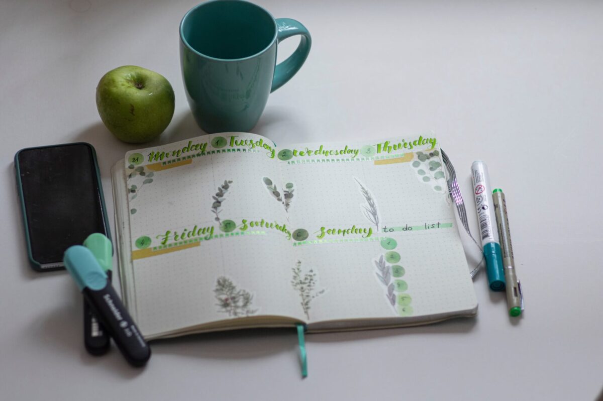 Notebook, markers, apple, and a mug