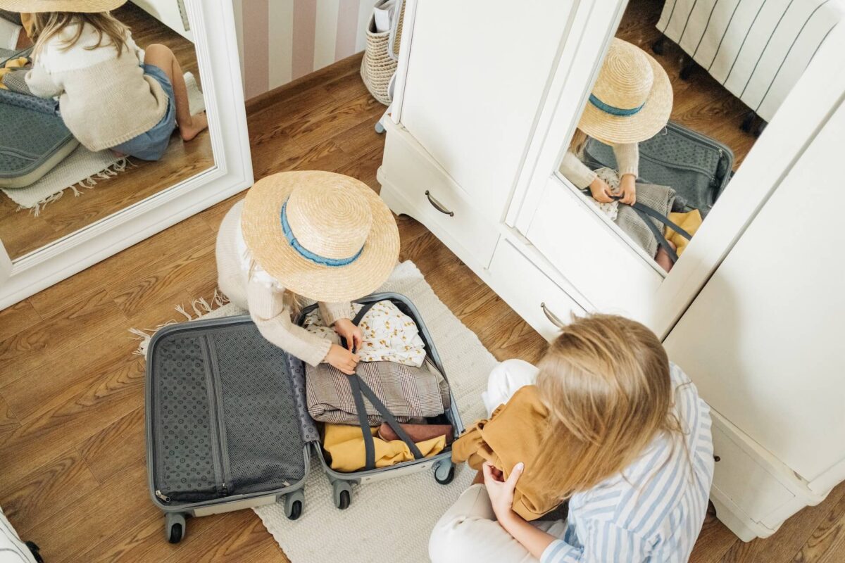 Two persons placing clothes in a suitcase
