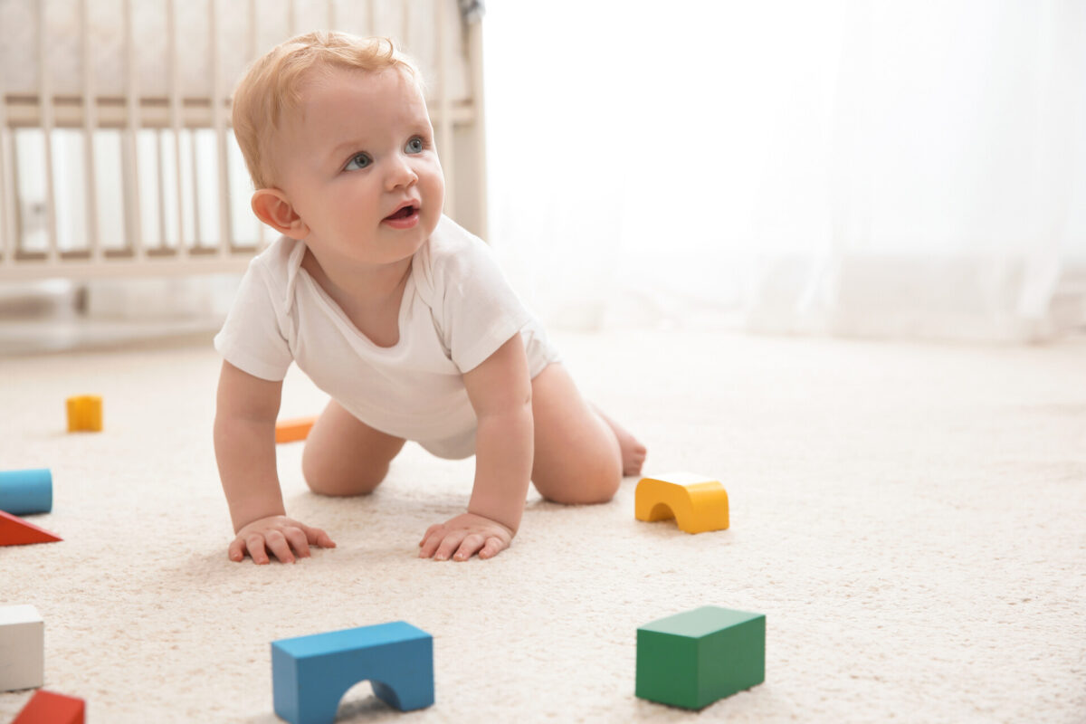 baby crawling on the floor playing with his blocks