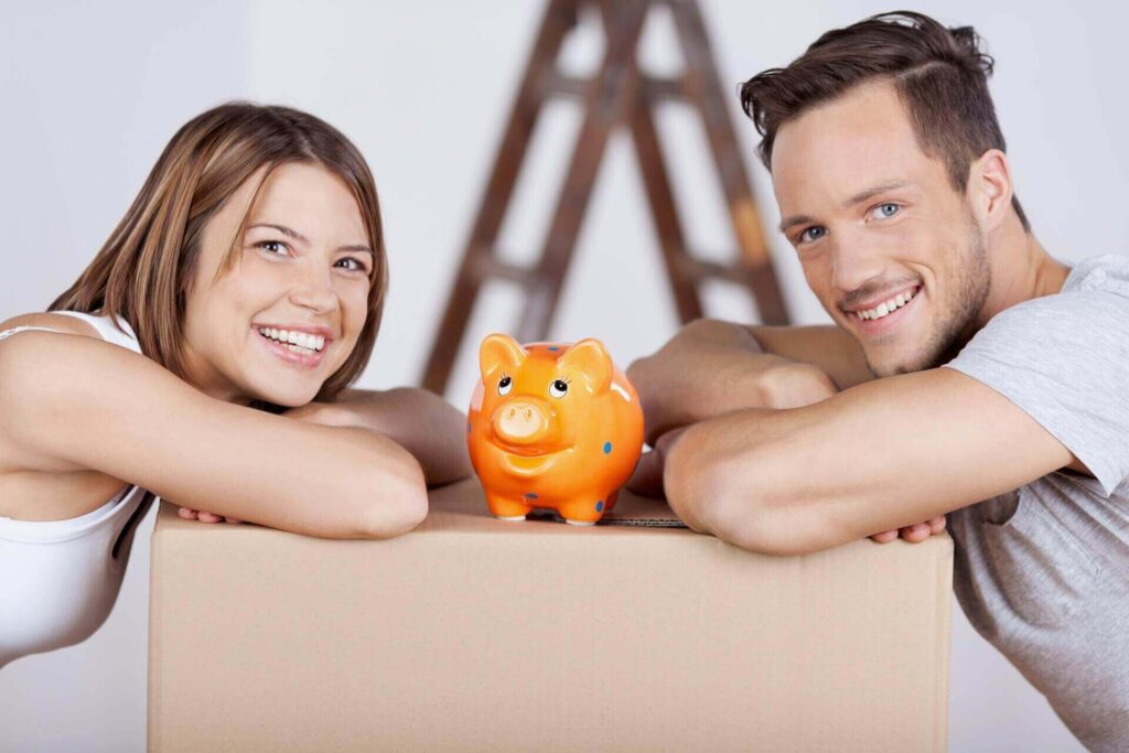 A couple leaning on boxes with a piggy bank