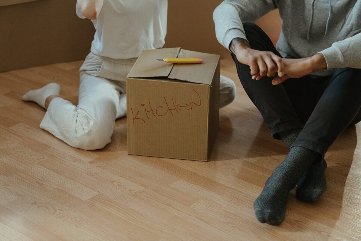 Two people sitting on the floor next to a box