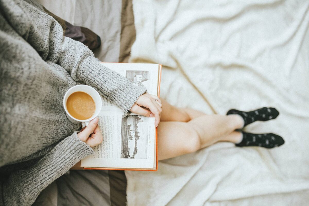A woman drinking coffee and reading a book