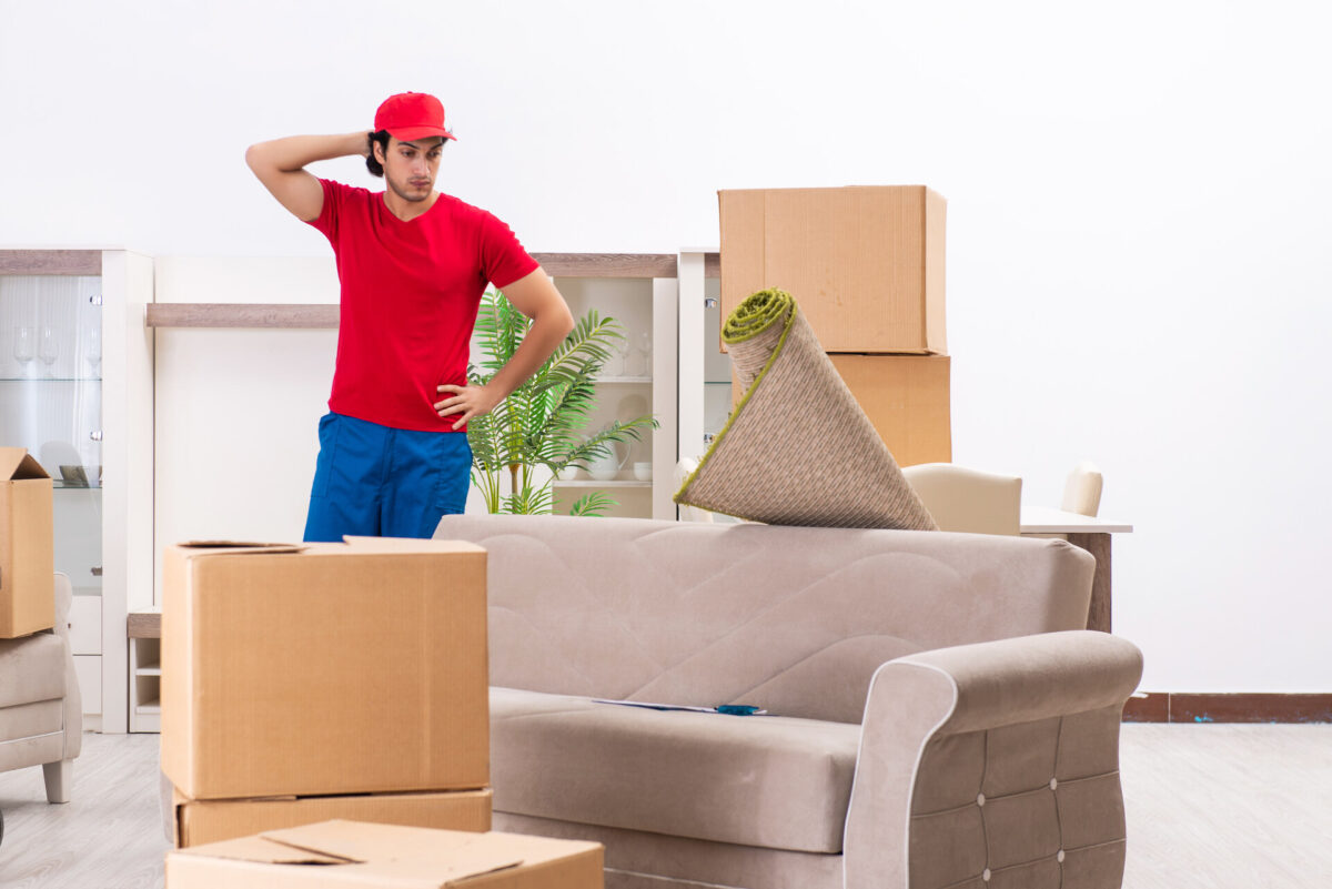 A mover standing next to a couch and boxes