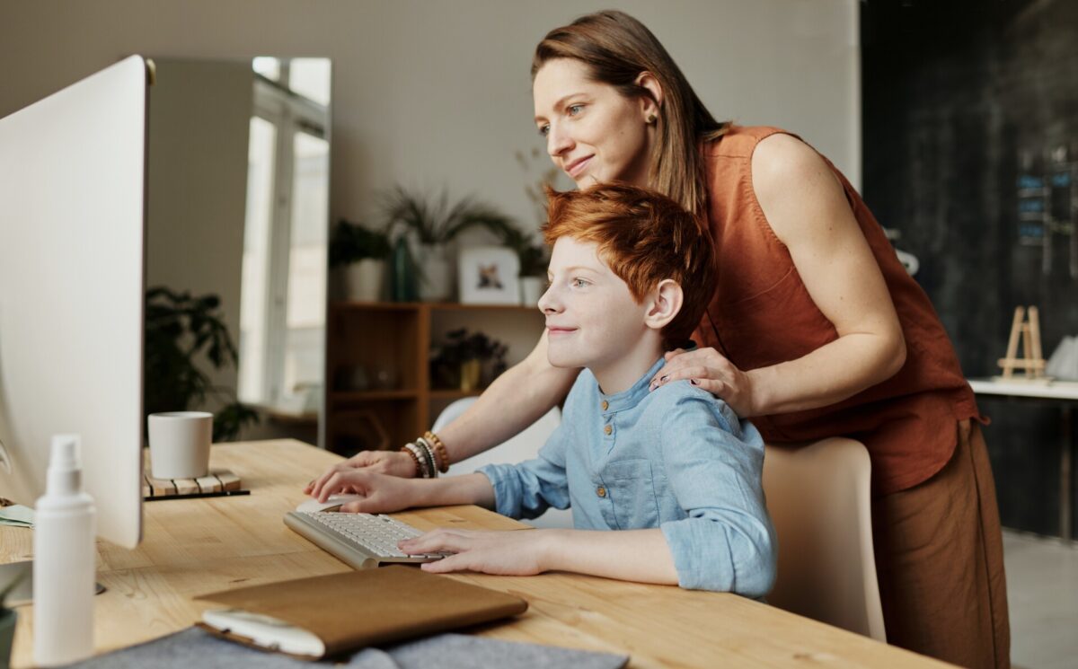 A smiling mother teaching a son how to use the computer