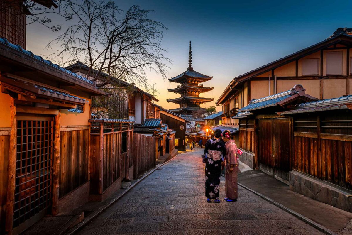 Two women in kimonos standing on the street