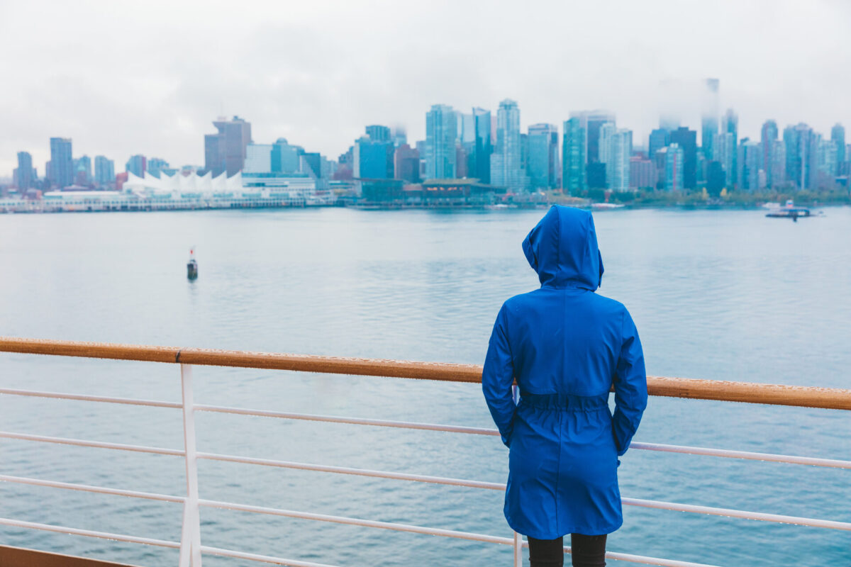 A woman standing on a boat with a raincoat on after moving abroad