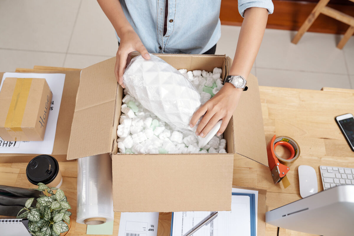 Man packing a vase in a box with foam peanuts