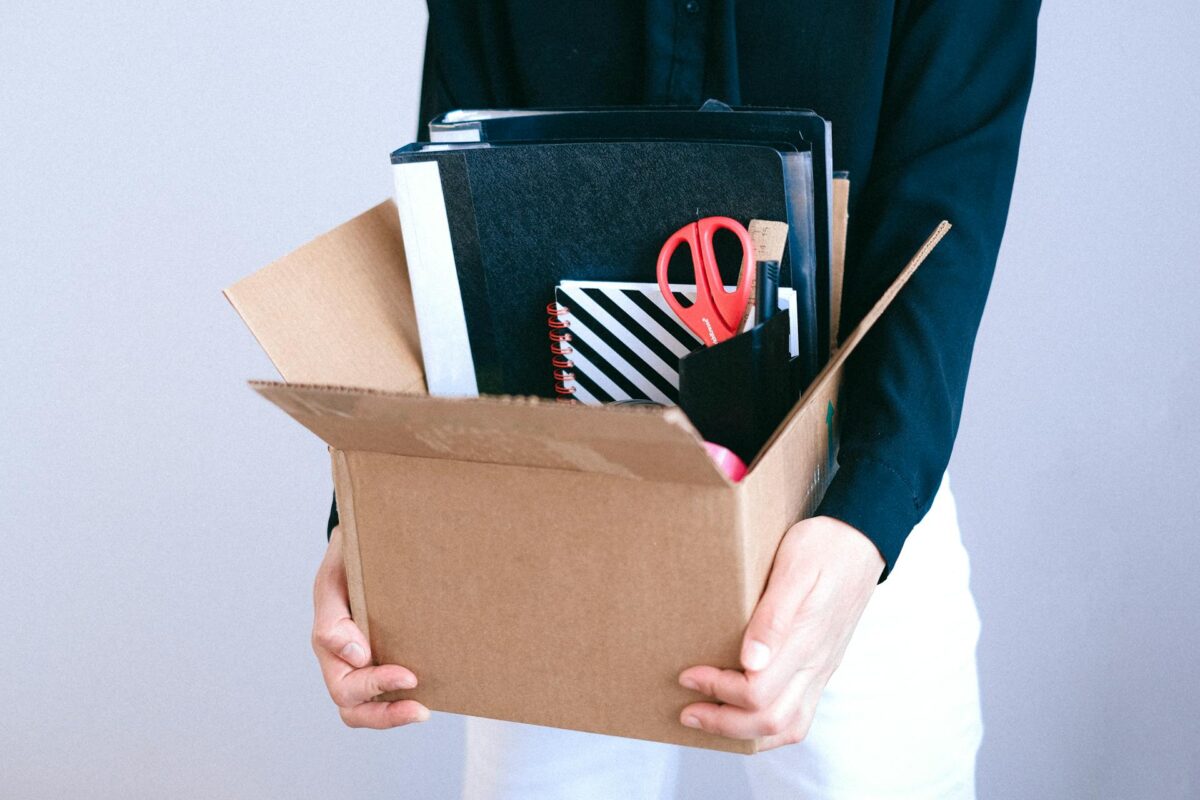 a woman holding a box with office supplies